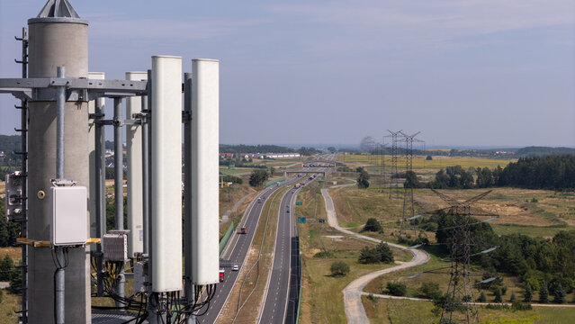 Aerial view of a telecommunications tower with antennas overlooking a highway stretching through the landscape in Gdansk, Poland.