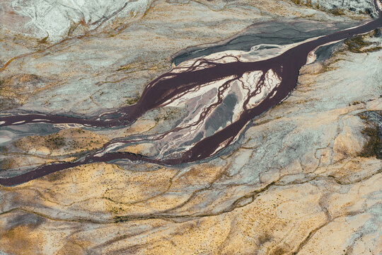 Aerial view of Power Plant Ash Disposal with dark braided streams flowing through barren textured terrain in Poland.