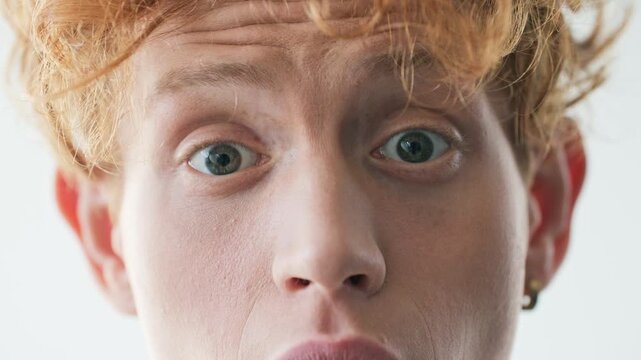 Surprised Caucasian man looking into camera with wide open eyes and shocked expression. Close up portrait male showing amazement disbelief and strong human emotion against clean background.