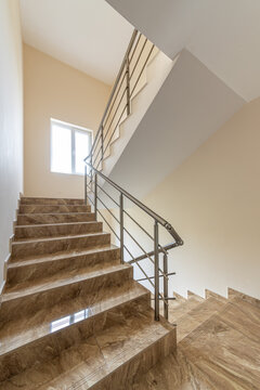 Modern stair case between floors. Stairs with metallic rail in modern building. Interior of a contemporary apartment or office building. Architecture and real estate background.