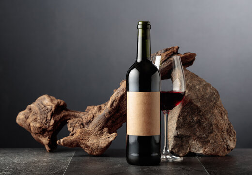 Red wine with old snag and a piece of granite rock on a black background.