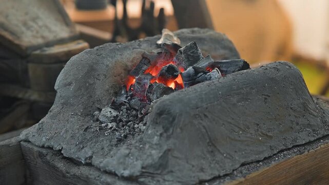 A blacksmith works at an anvil, heating metal in a forge. The glowing coals and tools surround the craftsman, showing the skill involved in metalworking