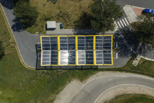 Aerial view of a modern solar panel carport structure with yellow frames, situated in a parking area surrounded by green grass and paved roads in Zwolle, Overijssel, Netherlands.