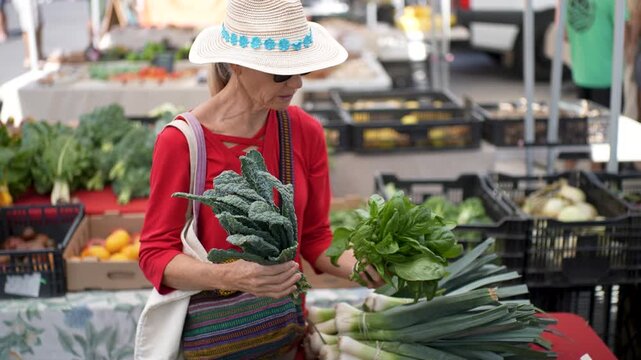 A woman smiles as she selects fresh vegetables and fruits at the Sonoma Farmers Market on a bright sunny morning.