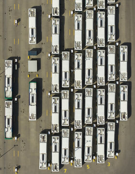 Aerial view of rows of white buses parked in an organized depot with yellow markings on the asphalt in Zwolle, Overijssel, Netherlands.