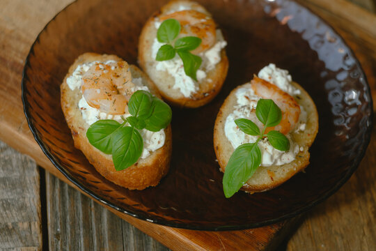 Bruschetta or crostini with cream cheese, shrimp garnished with fresh basil