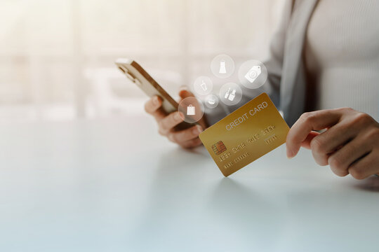 Businesswoman holding a gold credit card and smartphone for online purchasing, secure digital payments, mobile banking, and modern ecommerce solutions in a cashless business environment.