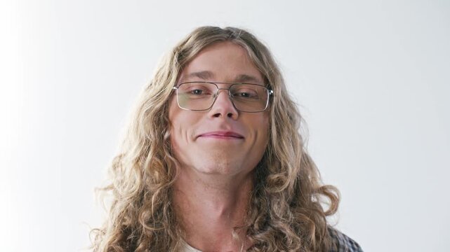 Handsome Caucasian man smiling at camera with confident expression. Portrait male wearing eyeglasses and showing long curly hair against clean background. Natural lifestyle and personality.