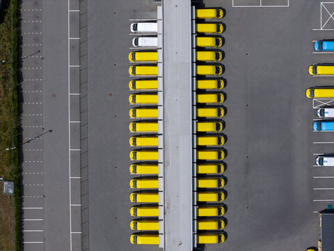 Aerial view of rows of yellow delivery vans parked in a logistics center in the Netherlands.