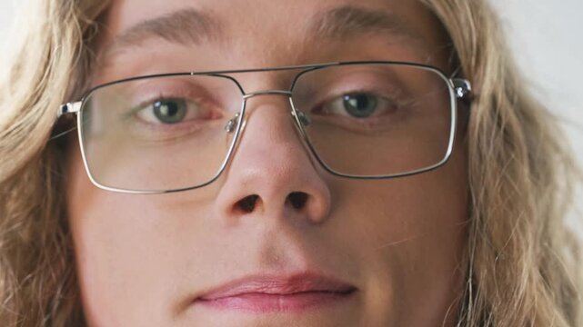 Detailed portrait Caucasian man looking into camera with blue eyes and confident expression. Close up male face wearing eyeglasses showing natural appearance and modern lifestyle indoors.