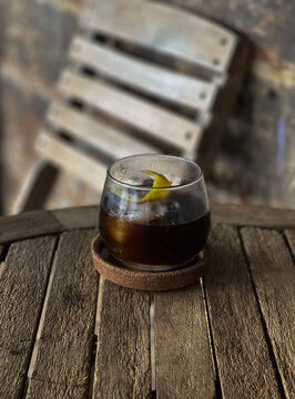 Refreshing iced black coffee with lemon Peel in clear glass, placed ona wooden table 