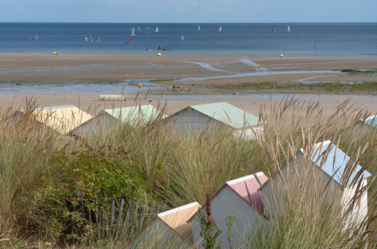 Saint-Aubin-Sur-Mer, France - 08 05 2026: View the jetty with colorful beach cabins, sand dunes, the beach and the sea with sun