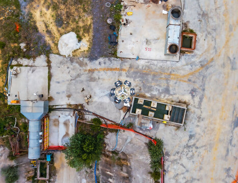 Aerial view of a construction site featuring industrial machinery, concrete foundations, and storage tanks on a dirt ground in Serravalle Scrivia, Piedmont, Italy.