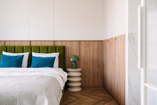 Modern hotel bedroom with gree headboard on bed and lamp on side table