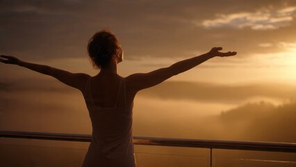 Fototapeta premium A young woman practicing mindfulness welcomes a new day with open arms on her balcony at sunrise enveloped in soft golden light and a peaceful morning ambiance