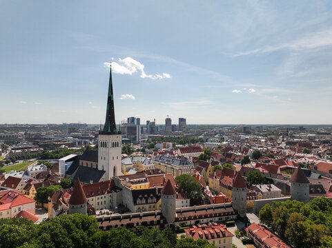 Aerial view of St. Olaf's Church surrounded by historic red-tiled rooftops and the city skyline of Tallinn, Harju County, Estonia.