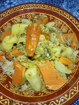 Traditional Moroccan couscous with steamed vegetables and tender meat in authentic clay dish