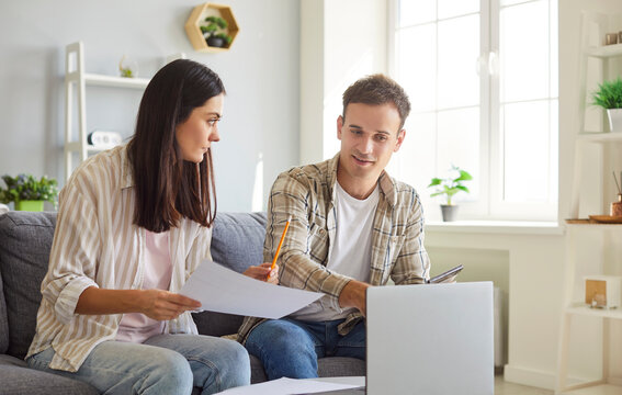 Family couple working on a laptop at home, managing money, documents, finances, and investments. They focus on their budget, balancing financial responsibilities during everyday life.