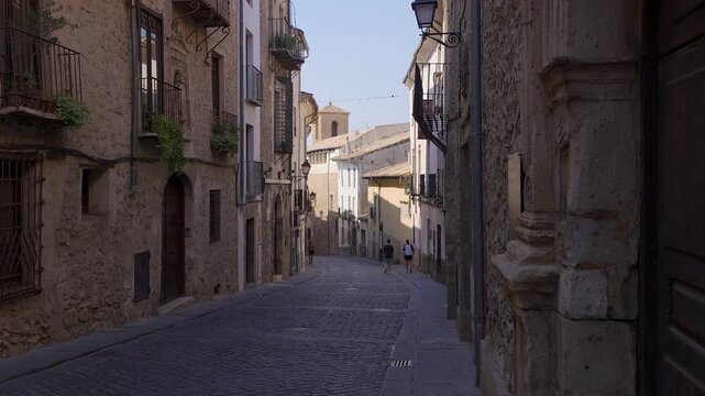 Narrow descending Calle San Pedro with balconies and street lamps in historic Cuenca Spain