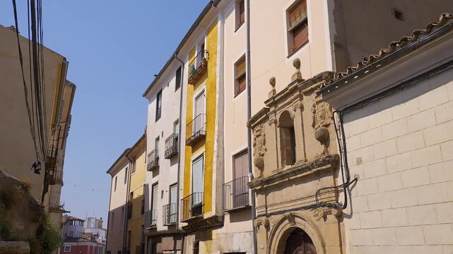 Ornate stone doorway among traditional houses on Calle San Pedro in historic Cuenca Spain