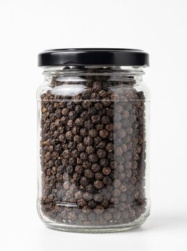 Black peppercorns in a glass jar with black lid isolated on white