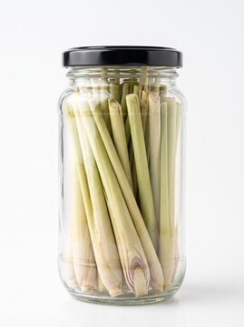 Glass jar filled with fresh lemongrass stalks on white background