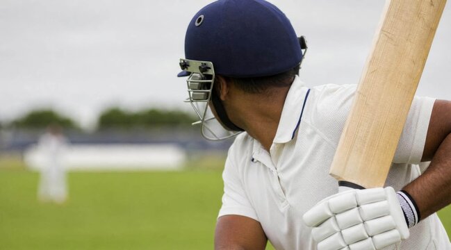 Professional cricket player preparing to bat on a field.