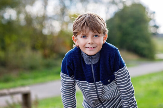 Smiling schoolboy leaning forward outdoors in a park with a cheerful expression and natural background