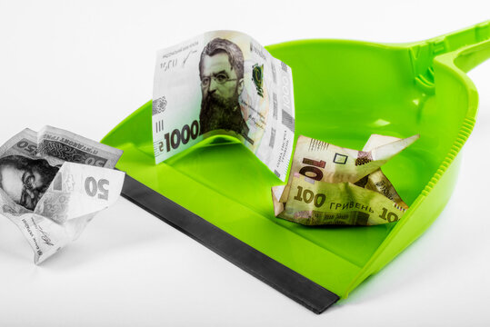 Green plastic dustpCrumpled Ukrainian hryvnia banknotes in green plastic dustpanan isolated on white background