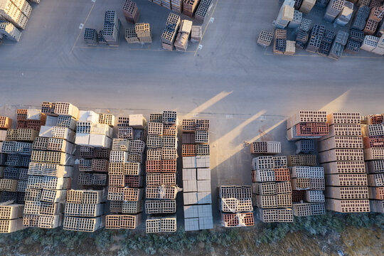 Aerial view of organized stacks of construction materials including bricks, pavers, and cinder blocks in a supply yard in Bluffdale, Utah, United States.