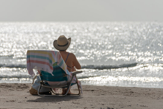 Unrecognizable person relaxing on beach chair facing the sea