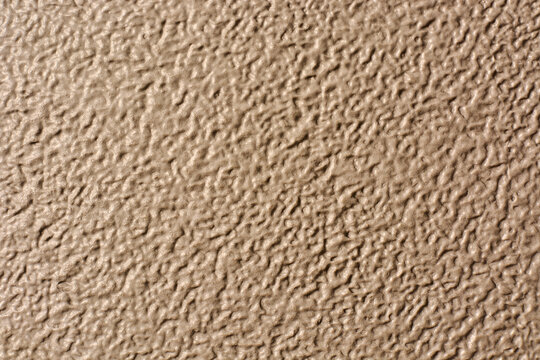 beige textured surface background, rough bumpy pattern and grainy tan finish, full frame close-up, industrial material or wall design concept