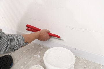 Fototapeta na wymiar Worker plastering white wall with putty knife indoors, closeup