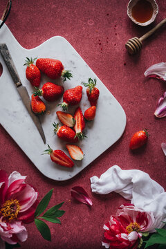 Strawberries on a marble cutting board with flowers