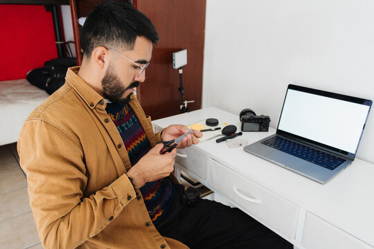 Content creator sitting in front of his desk using a pair of scissors.