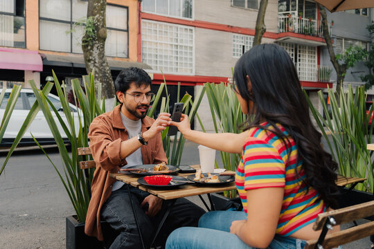 Couple sharing content on smartphone in a coffee shop.