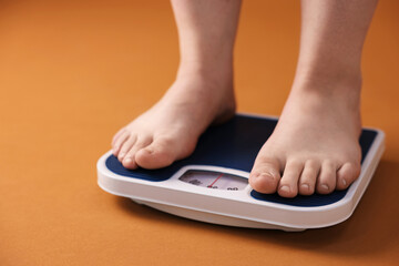 Fototapeta premium Overweight woman on scale against brown background, closeup. Space for text