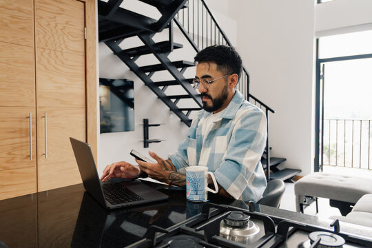 Young man working with laptop and smartphone at home