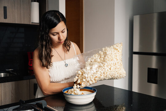Young woman serving popcorn in a bowl in the kitchen