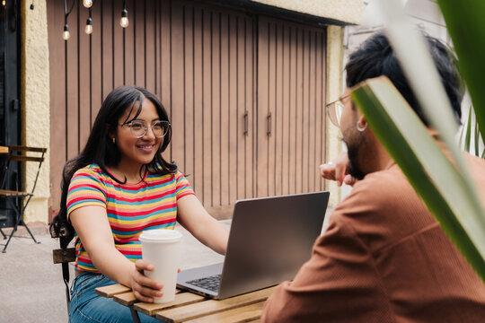 Young couple talking while working on laptop at outdoor cafe