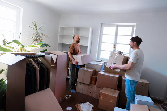 Two Men Moving Boxes In Bright New Apartment