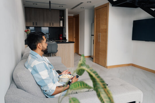 Man choosing a movie on television while eating
