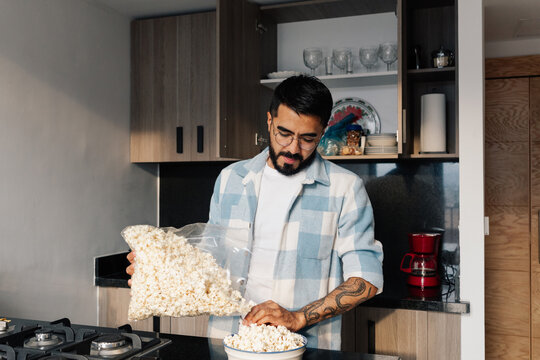 Young man serving popcorn in the kitchen