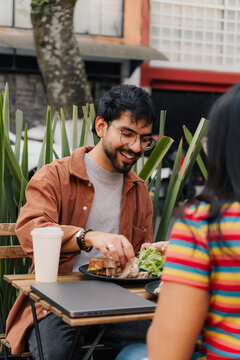 Smiling young man enjoying lunch on a terrace.