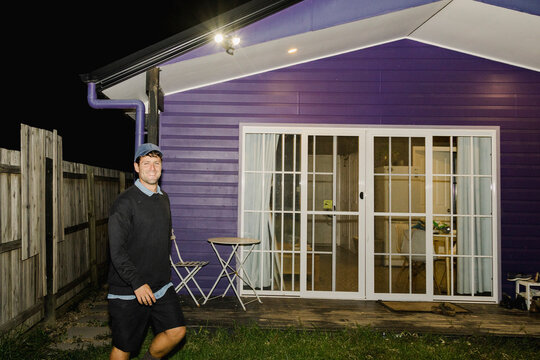 UGC Man smiling outside purple house at backyard night party