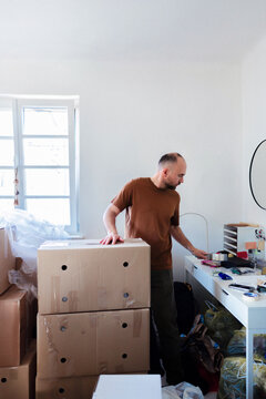 Man Unpacking Cardboard Boxes During Move In Bright Room
