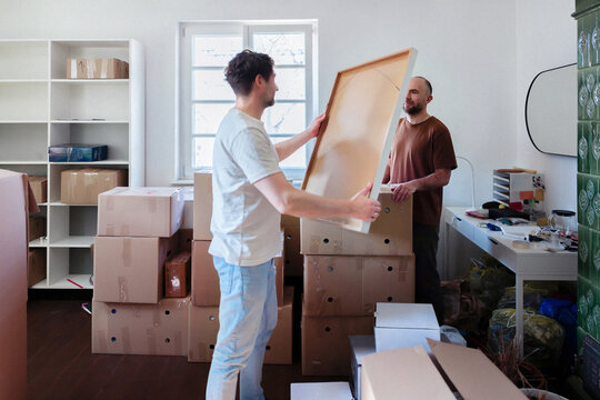Two Men Moving Into Apartment Together With Boxes