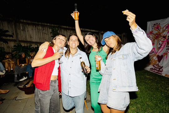 UGC Four friends cheering with drinks at backyard party
