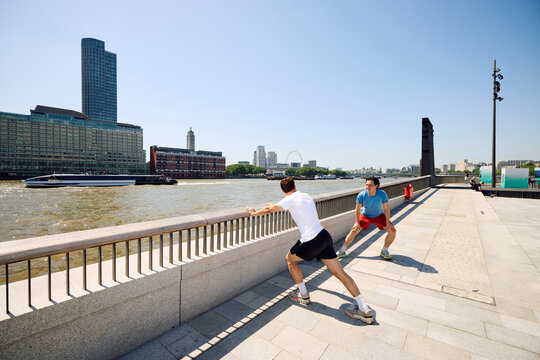 Two men exercise outdoors by the Thames River