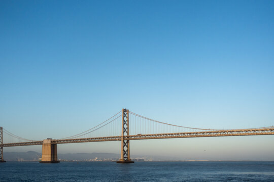 Bay Bridge Spans Water Under Clear Sky at Sunset